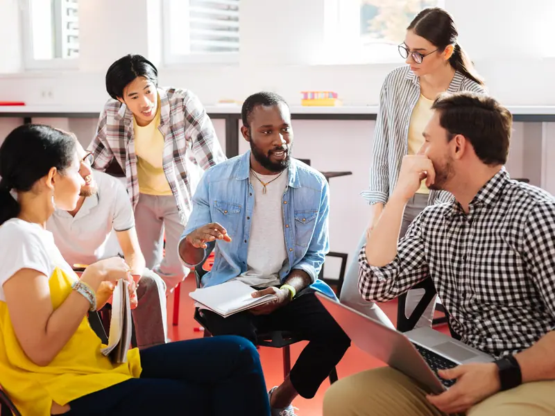 Des étudiants discutent autour d’une table avec leurs ordinateurs