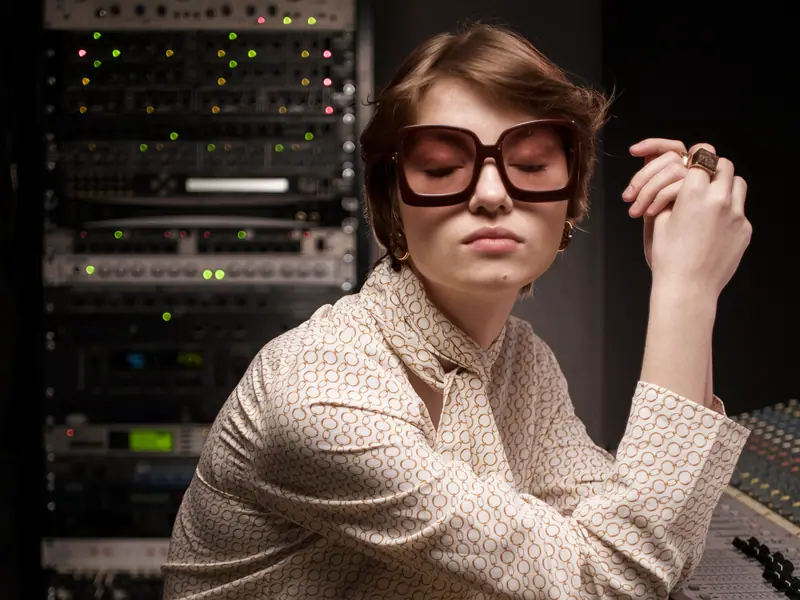 Une femme à lunettes assise à côté d’une baie de serveurs